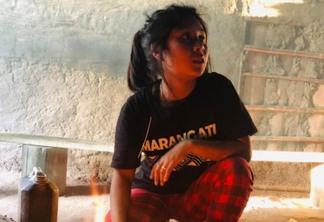Menina indígena sentada em frente à fogueira
