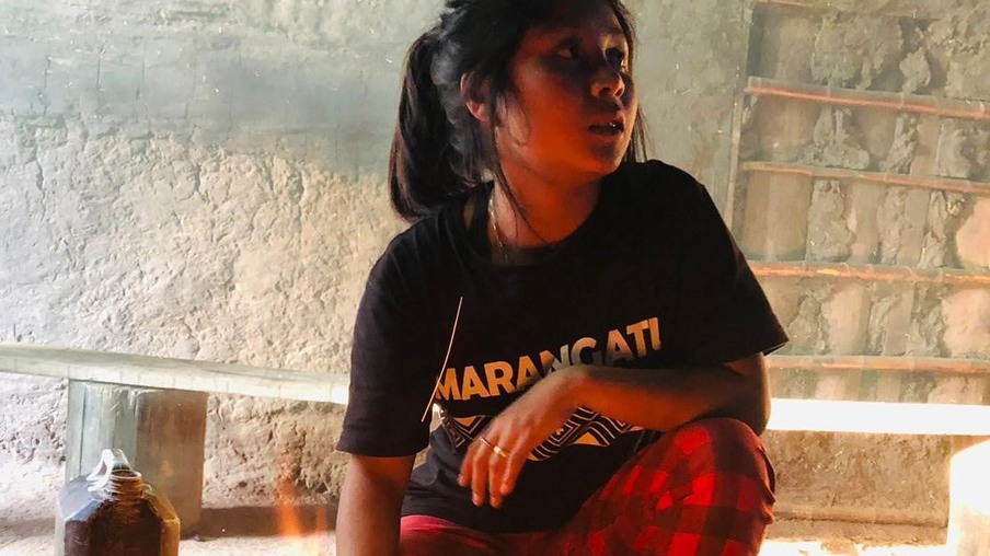 Menina indígena sentada em frente à fogueira