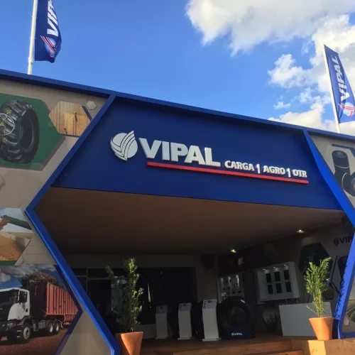 Estande da Vipal no evento, com pneus do lado de dentro, fotos aplicadas no estande com produtos da marca e duas bandeiras da marca no topo