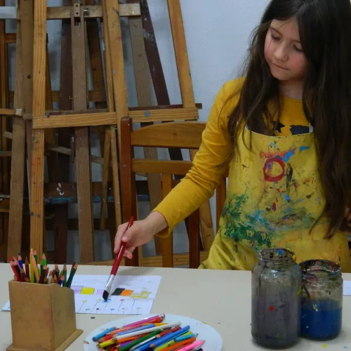 Uma menina pinta em uma mesa com diversos recursos. Foto: Divulgação