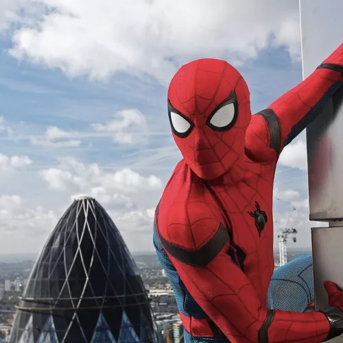 O super-heroi Homem-Aranha, grudado em uma parede. Atrás, a vista de Londres de cima.