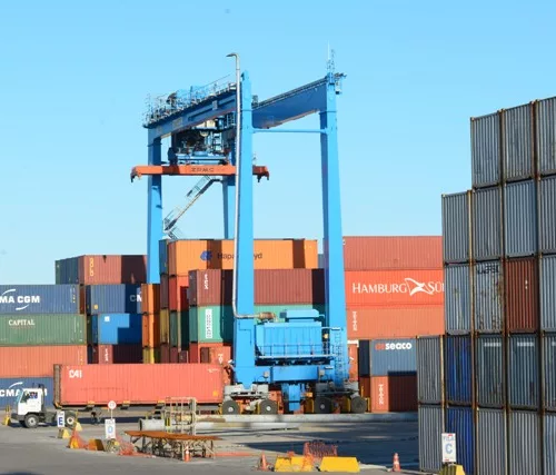Movimentação de terminal de containers em porto em um dia de céu azul.