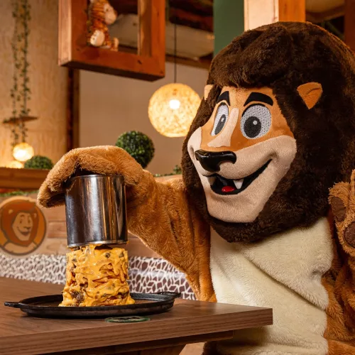 Em uma mesa da lancheria, o leão “Leonel”, mascote da Mundo Animal, destapa uma “torre de batatas”.
