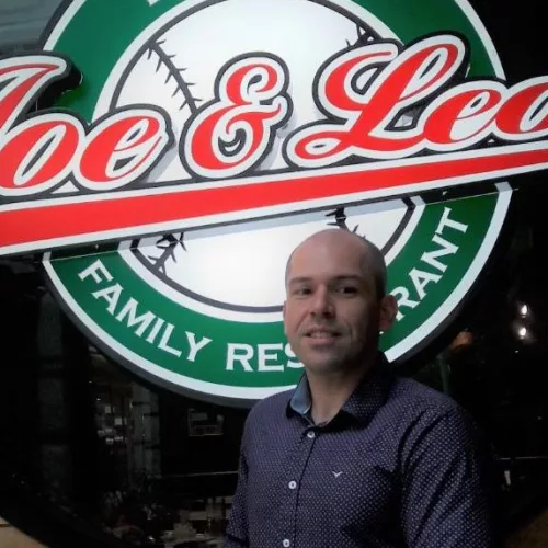 Um homem posa em frente à logomarca Joe & Leo's