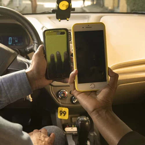 Mês da 99. Motorista e passageiro encostam seus smartphones.