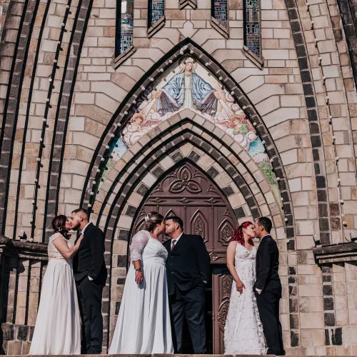 Royal Trudel. Casais de noivos se beijam em frente a catedral na Serra