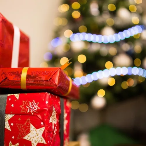 Compras, presentes, árvore de Natal ao fundo.