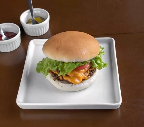 Hambúrguer em um pratinho quadrado e dois recipientes de molho.