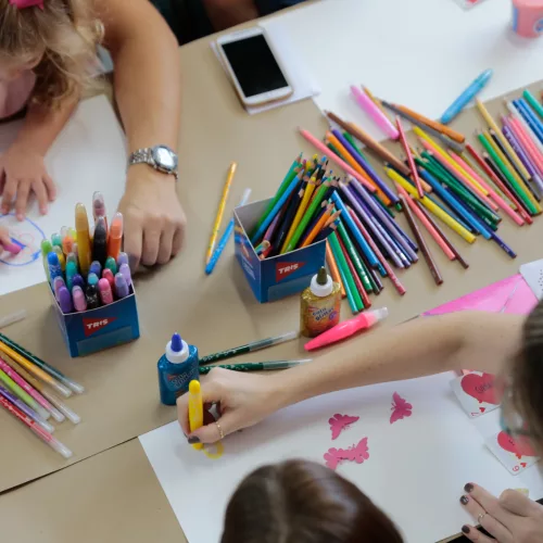TRIS. Pelo menos três crianças pintam com diversos lápis e canetas coloridas.