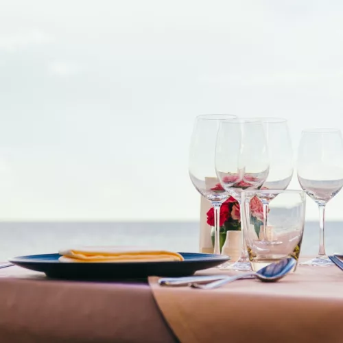 Fouet Gastronomia. Mesa, pratos e copos com o mar ao fundo.