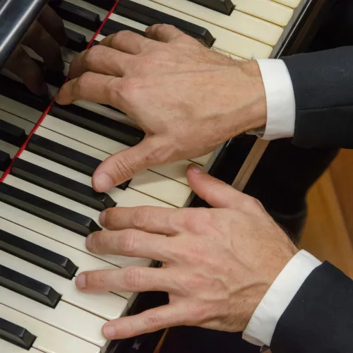 Mãos tocam piano.