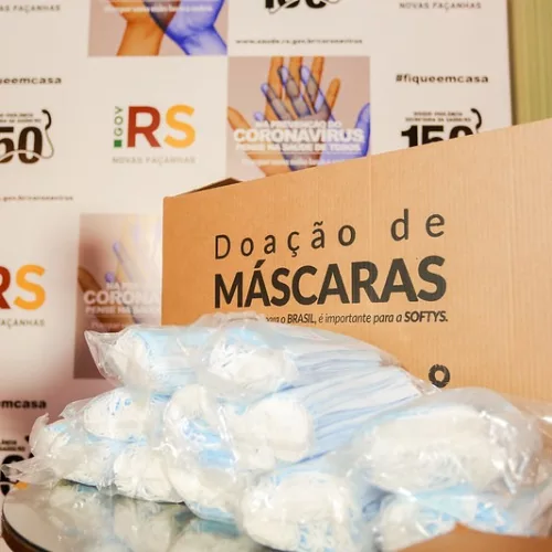 CMPC caixa com doação de máscaras e logos do governo ao fundo