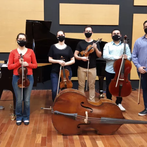 Músicos no palco da OSPA, com seus instrumentos: piano, violino, violoncelo, contrabaixo, todos de máscara.