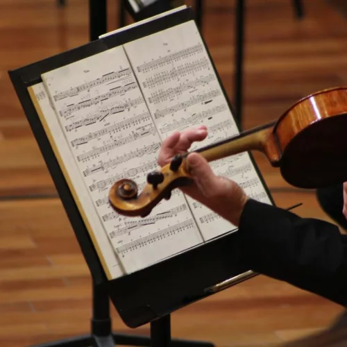 Mozart e Dvořák; partitura e braço de uma pessoa tocando violino.