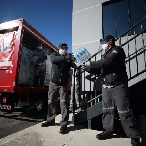 Dois homens carregam caminhão da Coca-Cola.