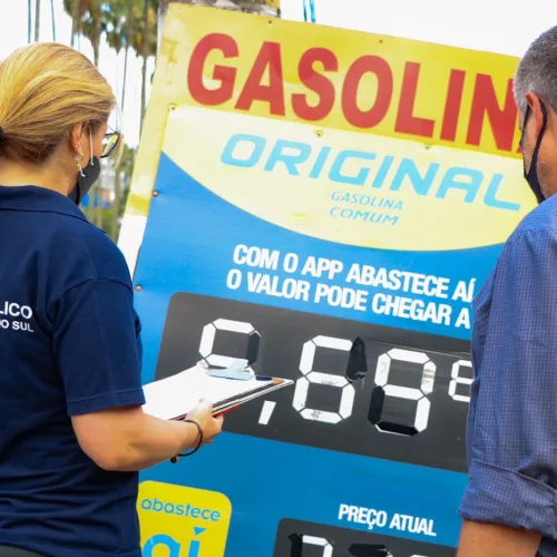 Membros do Ministério Público verificam placa com preços de combustíveis em Porto Alegre.