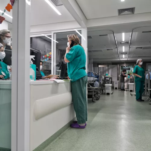 Enfermeiros com uniforme verde e utilizando máscara em um ambiente hospitalar