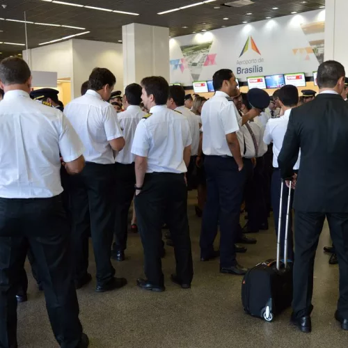 Os aeronautas e aeroviários de uniforme com camisa branca e calça escura paralisam as atividades em um aeroporto