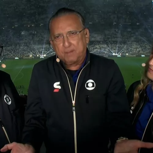 Galvão Bueno ao centro da imagem. Ao lado dele o comentarista Júnior e, do outro lado, Ana Thaís Matos. Ao fundo o estádio Lusail.