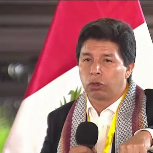 Pedro Castillo, presidente do Peru, discursa com microfone na mão direita. Ao fundo, a bandeira vermelha e branca do país latino-americano.