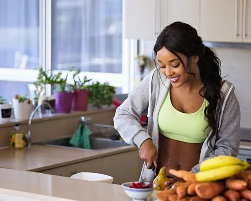 Mulher cortando frutas e legumes em uma cozinha