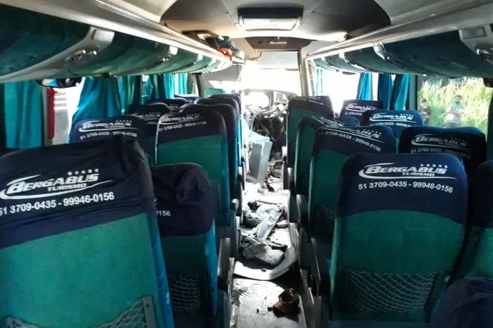 imagem interna do ônibus também com danos. A imagem mostra bancos verdes avariados e peças destruídas no chão do veículo