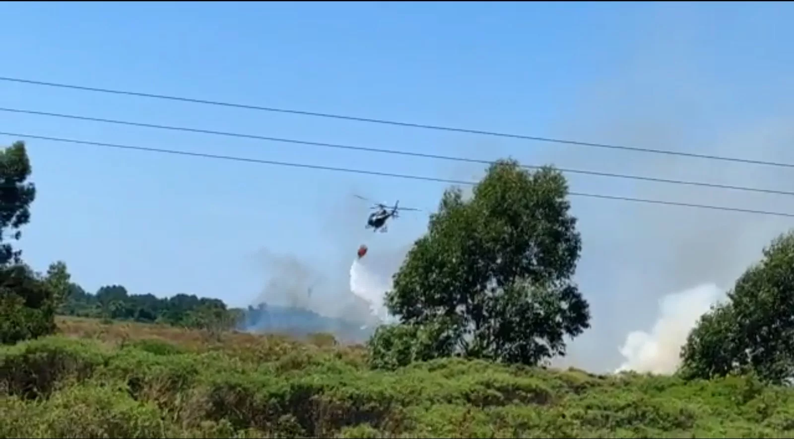 Helicóptero da Polícia Civil joga água nas chamas para tentar contê-las