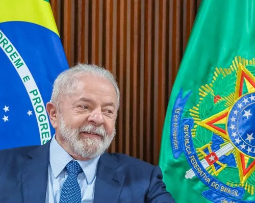 Presidente Lula de terno com as bandeiras do Brasil ao fundo