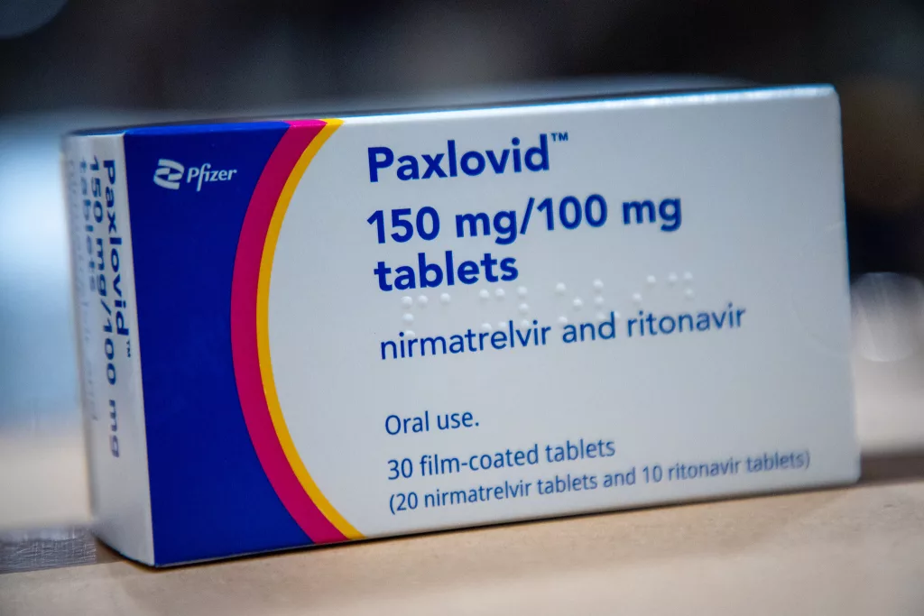 Caixa do medicamento Paxlovid, contra a Covid-19. Ela é branca, com letras e azul e uma faixa lateral em azul e outra em vermelho. 