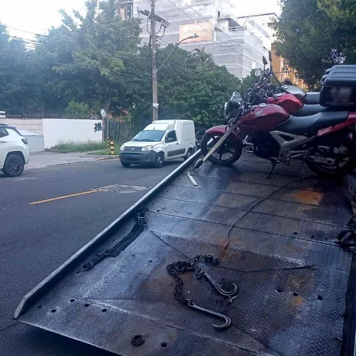 Três motocicletas apreendidas durante blitz em Porto Alegre são colocadas em cima de plataforma.